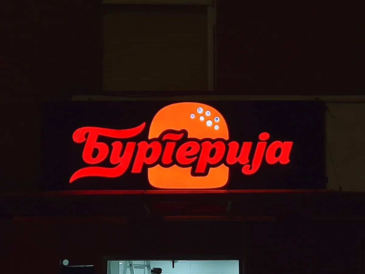 Svetleća slova Бургерија noću iznad ulaza u lokal