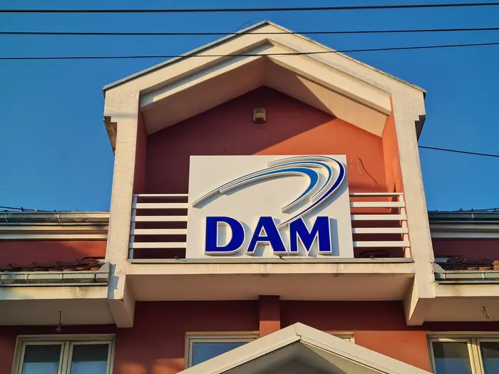 Reklamna tabla DAM sa plavim slovima, postavljena na zabat fasade