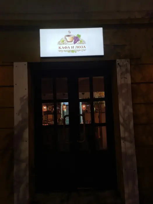 Light box sa natpisom КАФА И ЛОЗА iznad ulaznih vrata lokala noću