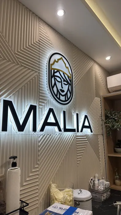 Logo i slova Malia sa pozadinskim osvetljenjem na zidu salona