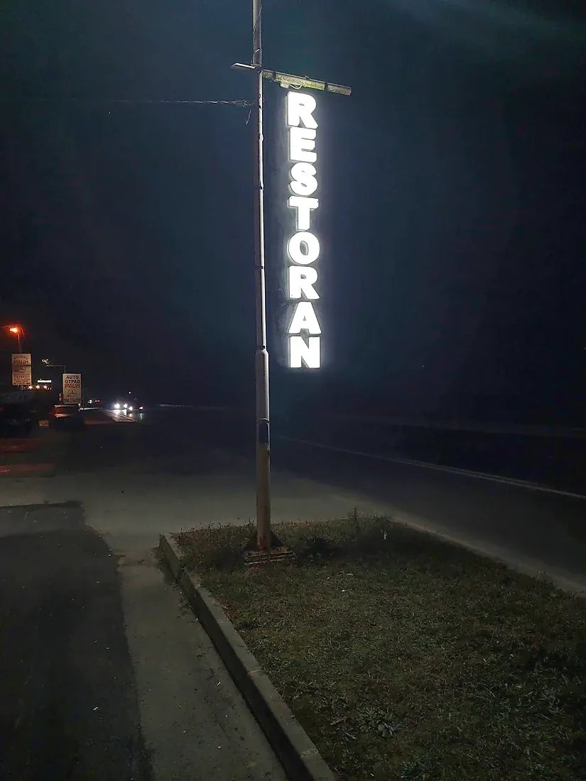 Svetleći totem RESTORAN pored puta noću