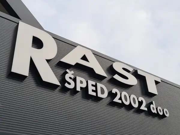 Bela 3D slova RAST ŠPED 2002 doo na sivoj fasadi